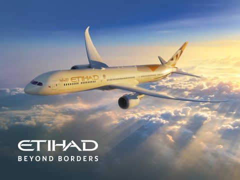 Etihad Airways Boeing 787 Dreamliner flying over Abu Dhabi cityscape at sunset. Luxury travel and international flights.