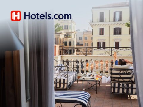 Person holding a smartphone showing Hotels.com app with a 10% discount offer for travel bookings and hotel deals.