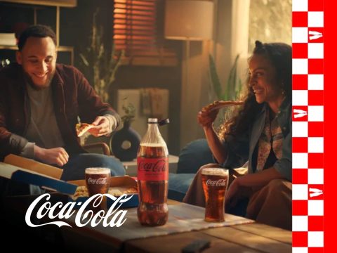 Coca-Cola bottle with condensation and ice cubes on a red background. Refreshing Coca-Cola drink.