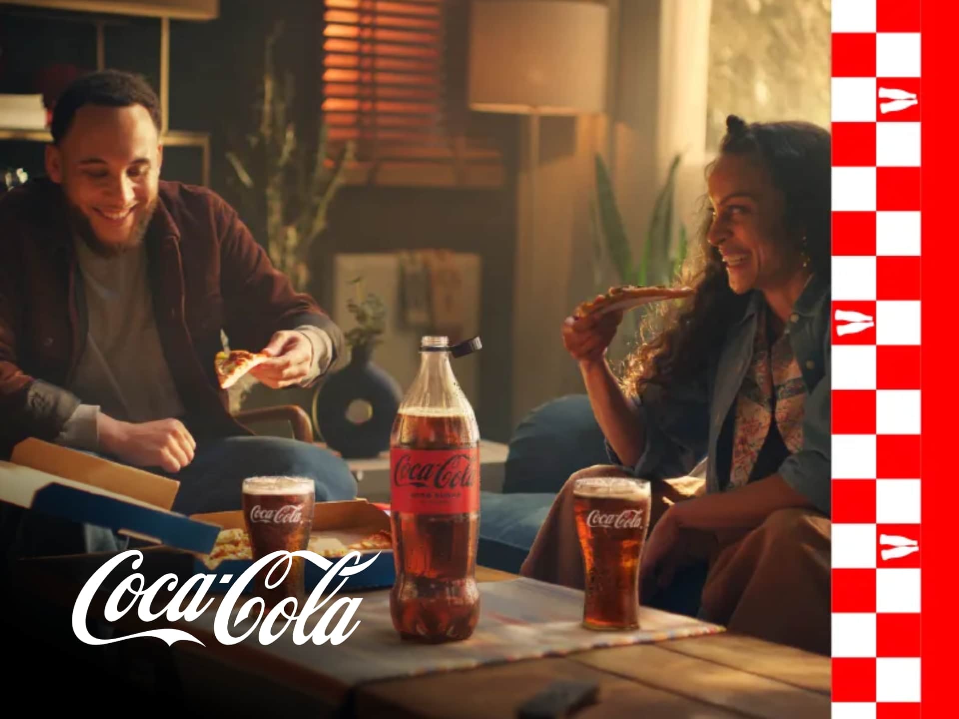 Coca-Cola bottle with condensation and ice cubes on a red background. Refreshing Coca-Cola drink.