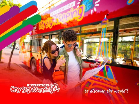 City Sightseeing City Sightseeing red double-decker bus tour in a vibrant city with landmarks. Explore attractions, book tickets, and enjoy city tours.