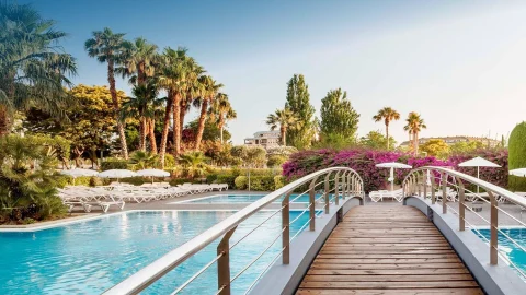 Luxury Aqua Hotel Group resort exterior featuring modern architecture and a sparkling swimming pool under a clear sky.