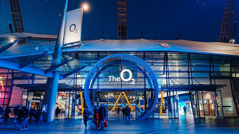 The O2 entrance pavilion and Icon Outlet illuminated in blue neon at night