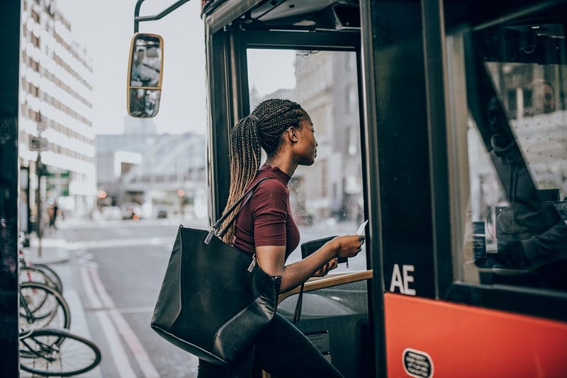London commuter boarding a red TfL double-decker bus on a city street