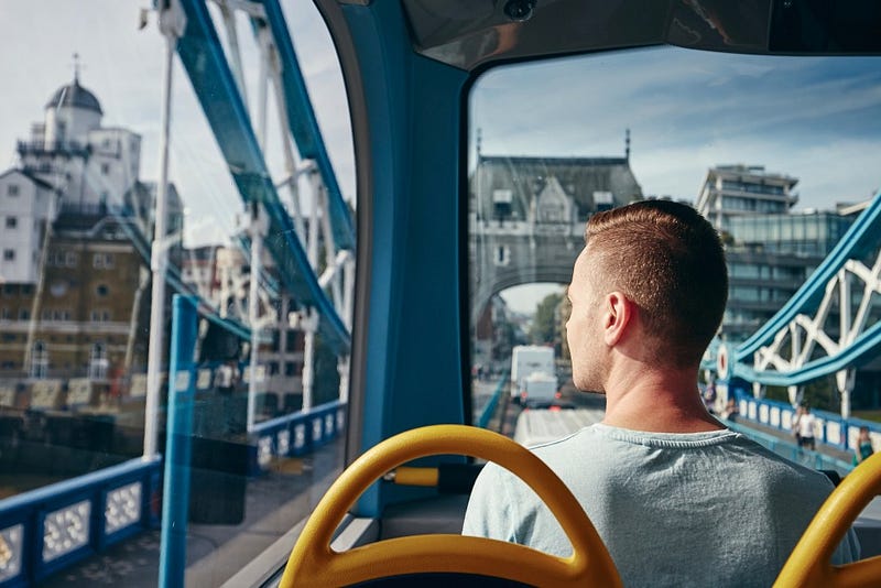 Passenger riding top deck of a London double-decker bus crossing Tower Bridge