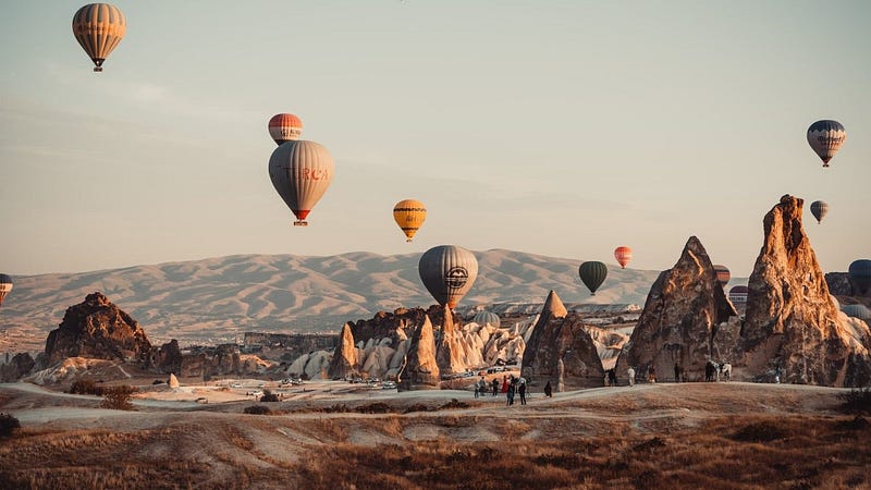 Scenic view of Cappadocia, Turkey: Fairy chimneys and hot air balloons at sunrise. Travel guide for Türkiye.