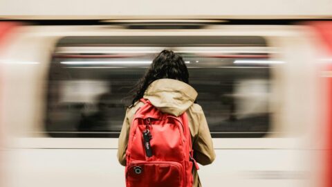 Insider Tips for Cheaper London Underground, TFL Bus & National Rail fares A person with a red backpack waiting as a train speeds past in the London Underground.