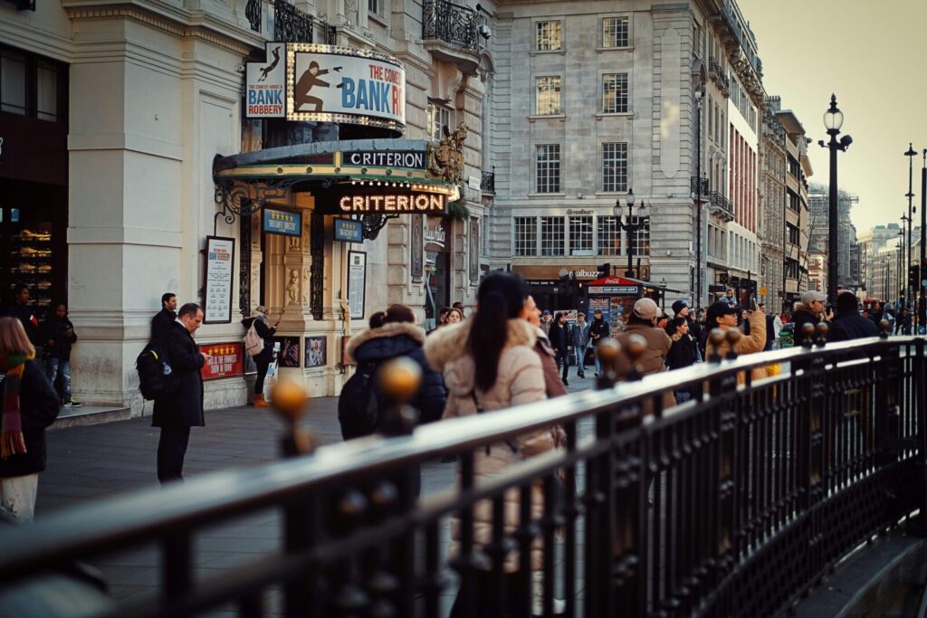 Busy street scene outside the Criterion Theatre in London's West End, featuring crowds near Piccadilly Circus.