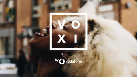 Young person using a smartphone, showcasing VOXI as a budget-friendly Vodafone dupe for mobile data savings.