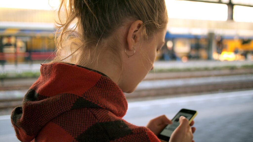 Woman checking smartphone for online shopping deals, browsing mobile offers & savings on a retail app.
