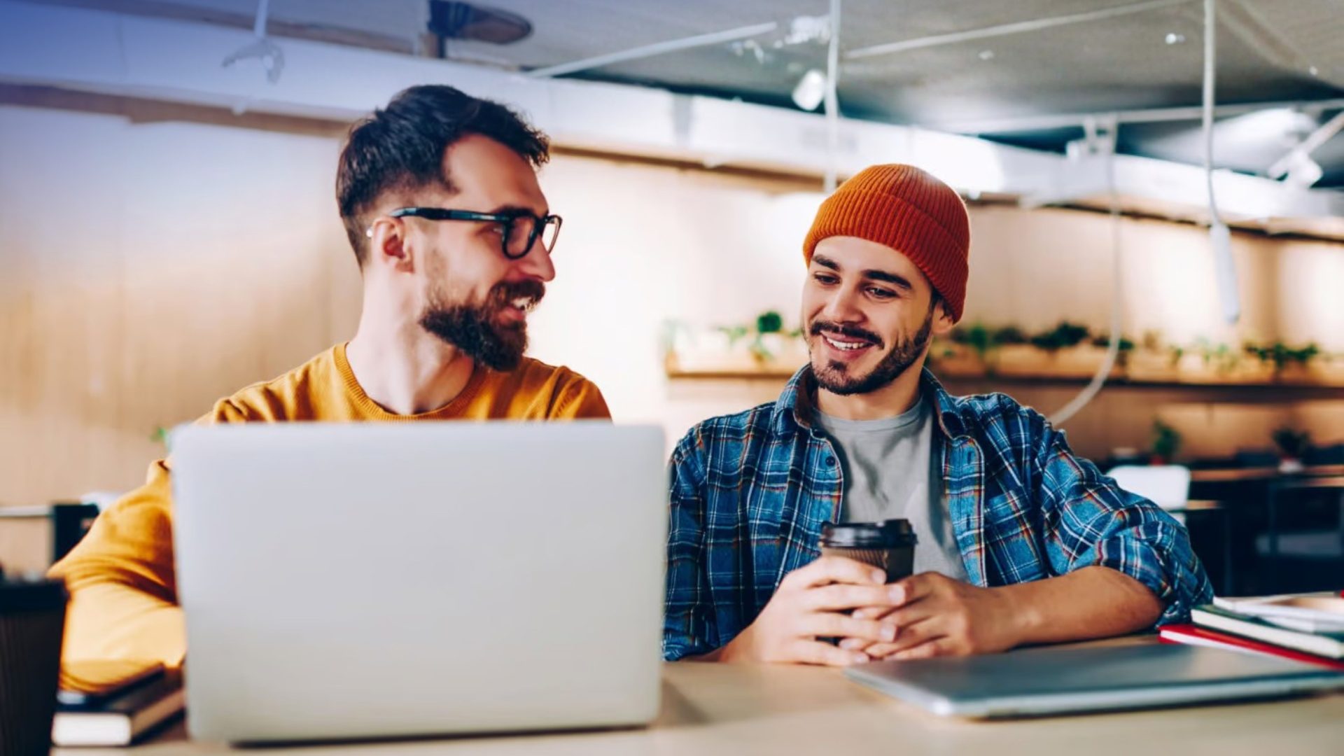 Two male entrepreneurs collaborating on a laptop in a modern co-working space in London.