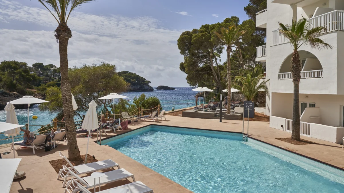 Luxury Barceló Hotels resort exterior featuring modern architecture, swimming pool, and palm trees under a sunny sky.