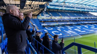 Panoramic view of the Stamford Bridge pitch during a Chelsea Stadium Tour in London, featuring the iconic blue seating.