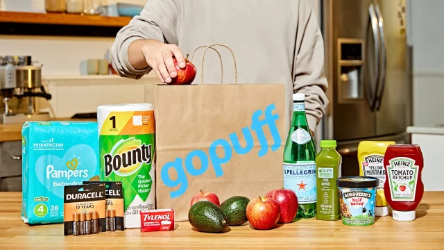 Gopuff delivery bag and smartphone app showing grocery shopping deals and rapid home delivery service options.