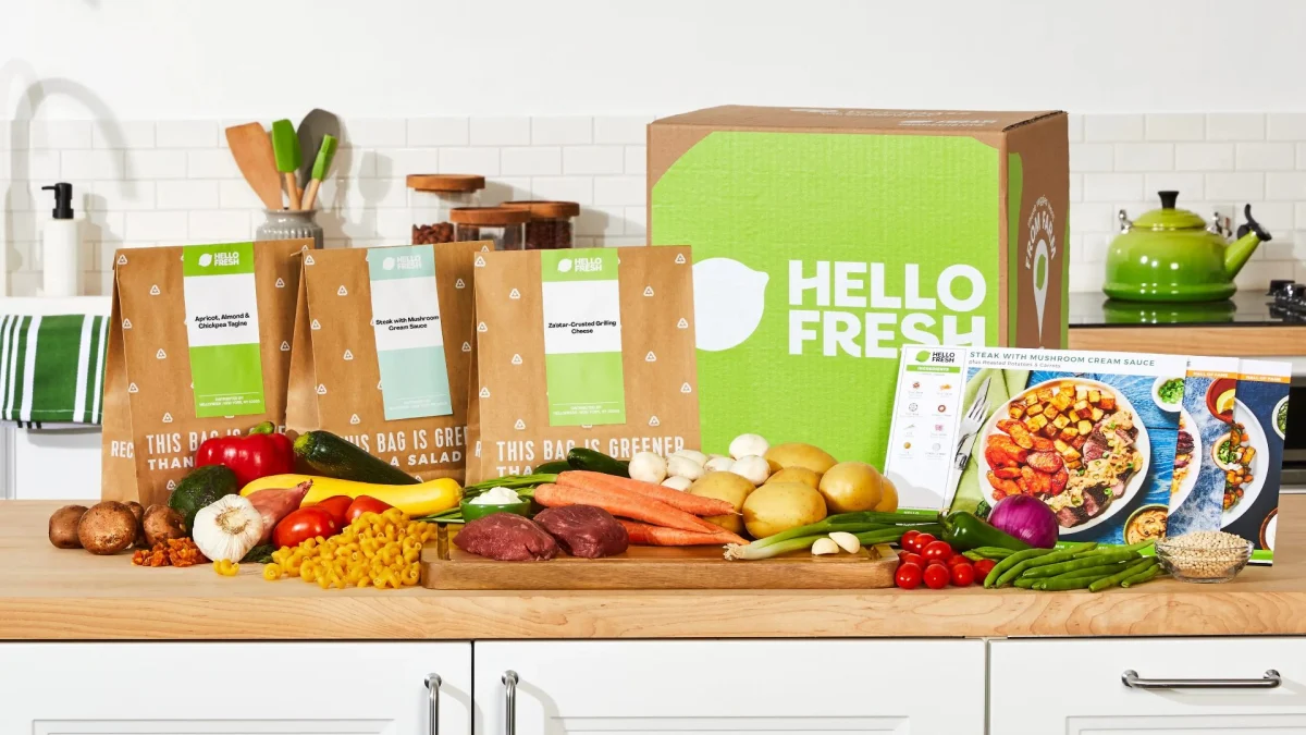 HelloFresh UK meal kit box with fresh ingredients and recipe cards on a kitchen counter for home cooking.