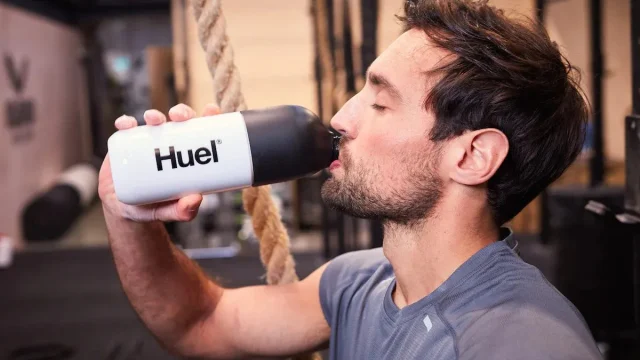 Huel nutritional meal replacement shake bottle and powder pouch on a clean kitchen counter for healthy living.