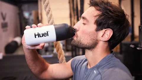 Huel nutritional meal replacement shake bottle and powder pouch on a clean kitchen counter for healthy living.