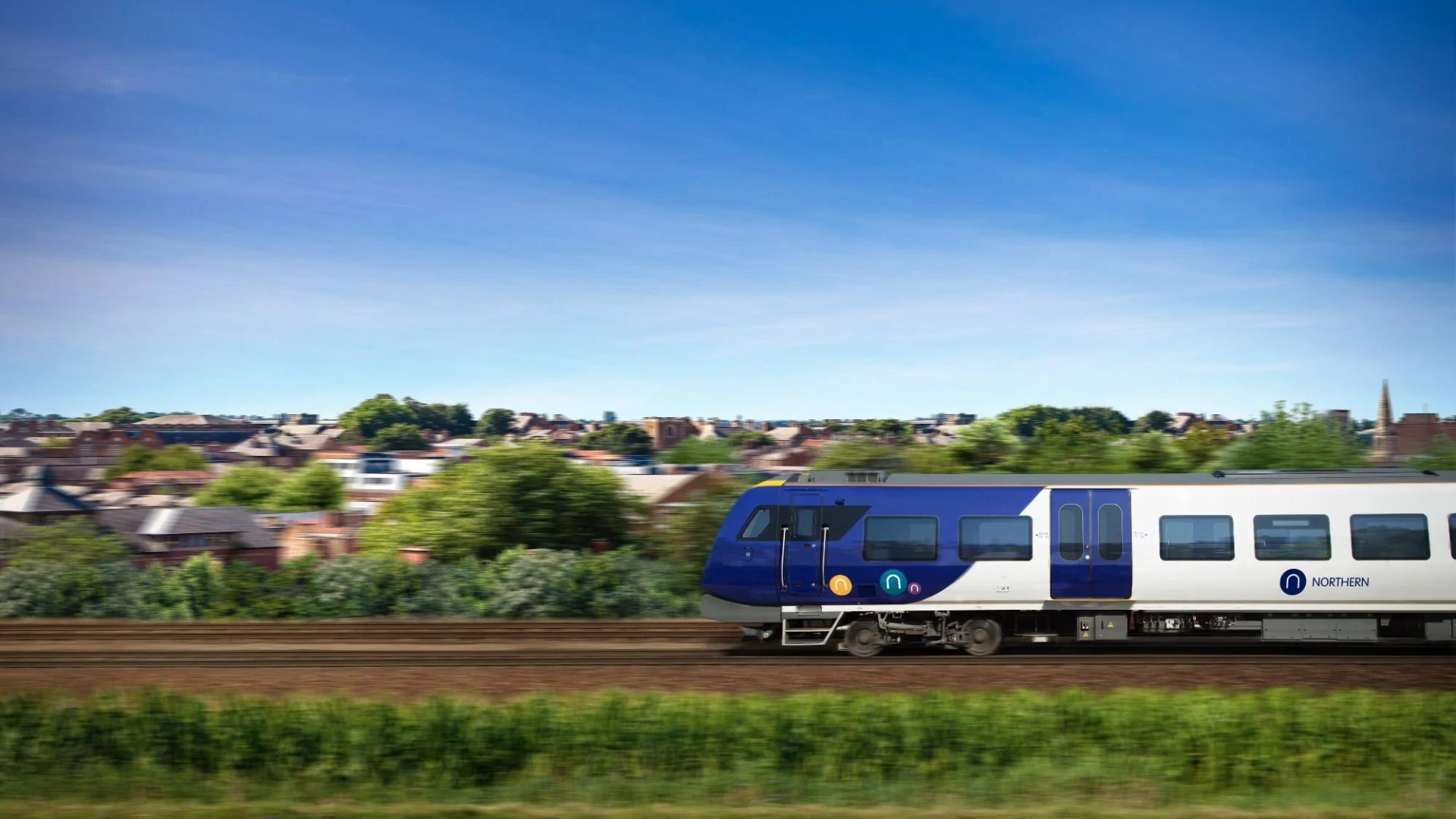 A modern Northern Railway train travelling through the scenic British countryside on a bright, sunny day.