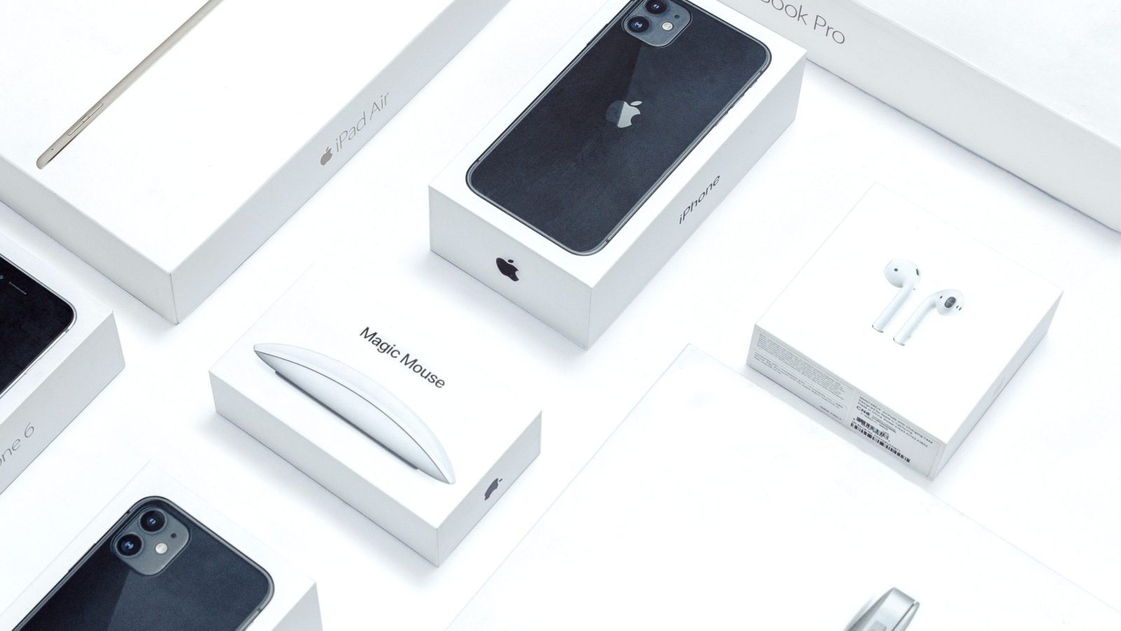 Official Apple product packaging and hardware flatlay with iPhone, AirPods, iPad Air, and Magic Mouse