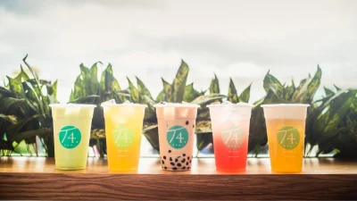 T4 Bubble Tea refreshing fruit tea drink with colourful tapioca pearls in a branded cup on a wooden table.
