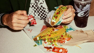 Taco Bell restaurant storefront featuring vibrant branding and promotional signage for meal deals and savings.