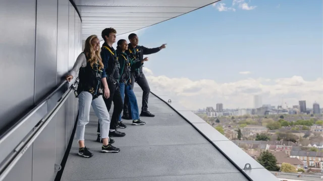 Visitors walking on The Dare Skywalk at Tottenham Hotspur Stadium, London, with panoramic views of the city skyline.