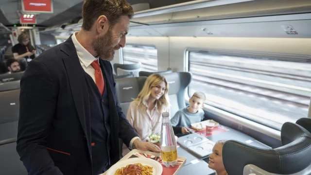 A modern Trenitalia high-speed train travelling through the scenic Italian countryside on a sunny day.