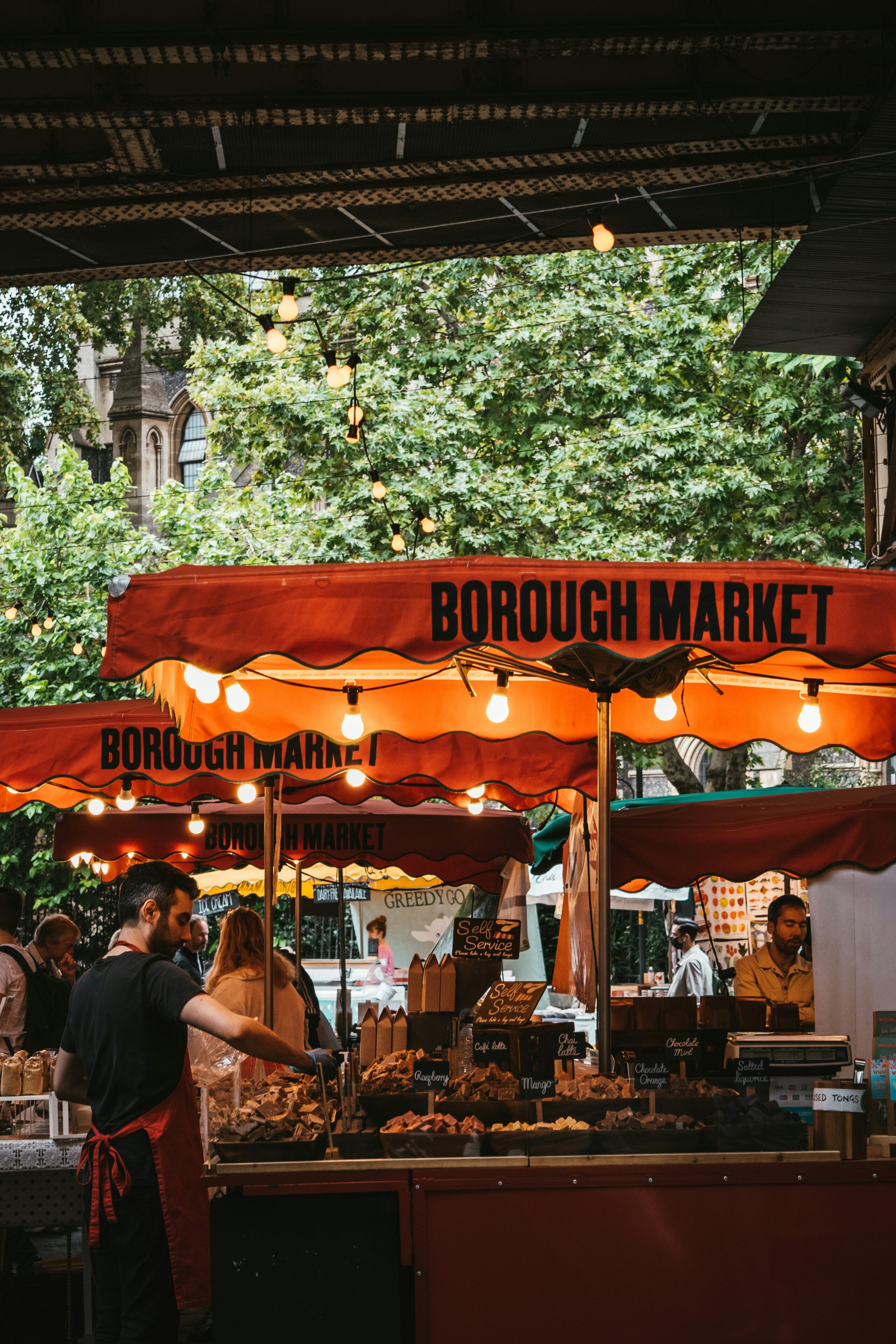 Borough Market food stall with orange awnings and warm festoon lighting in Southwark