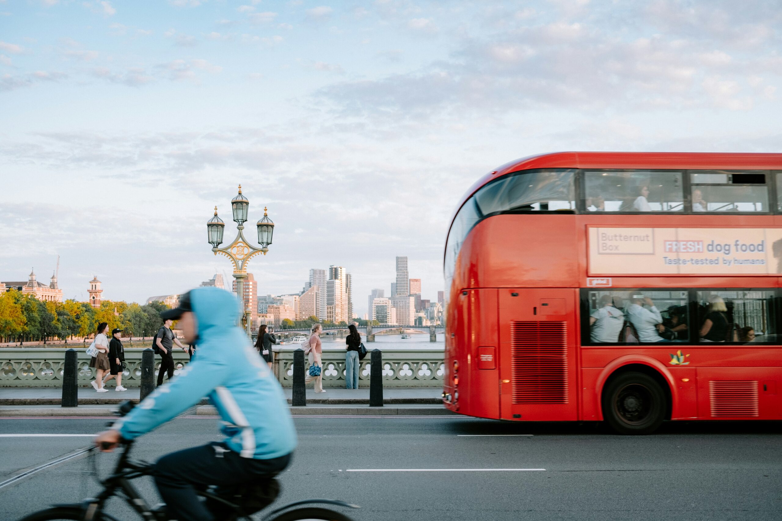 Cyclist riding across Westminster Bridge alongside a red London double-decker bus