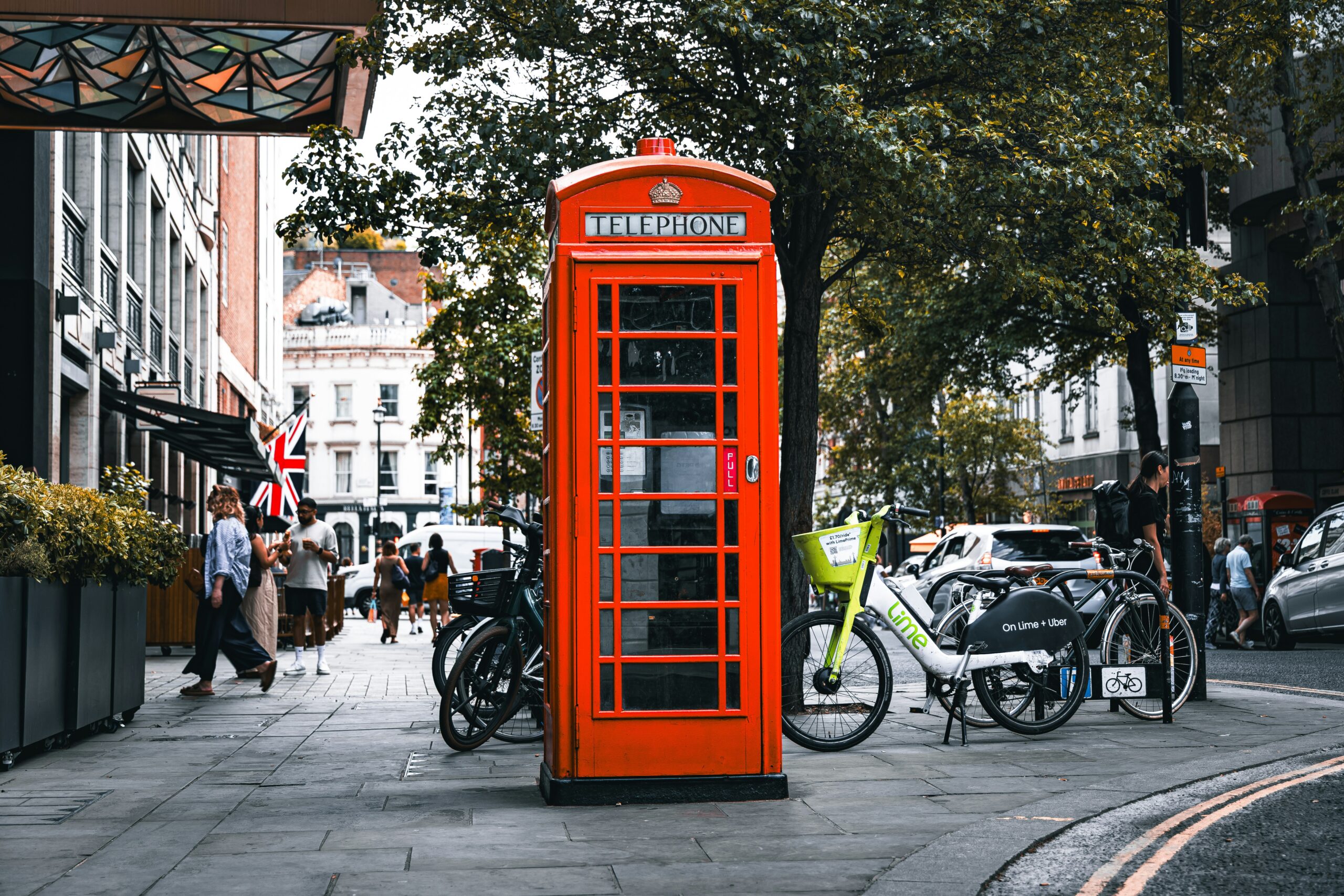 Green Lime electric rental bike parked beside a red telephone box on a London street