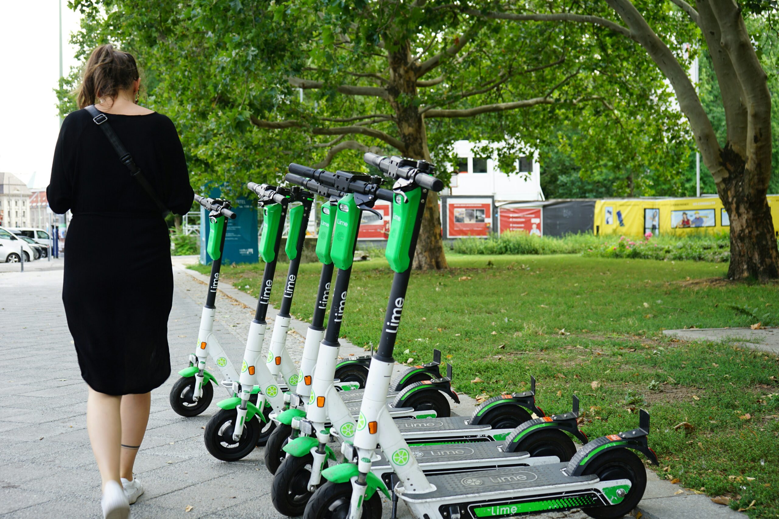 Fleet of green Lime electric rental scooters lined up on an urban pavement
