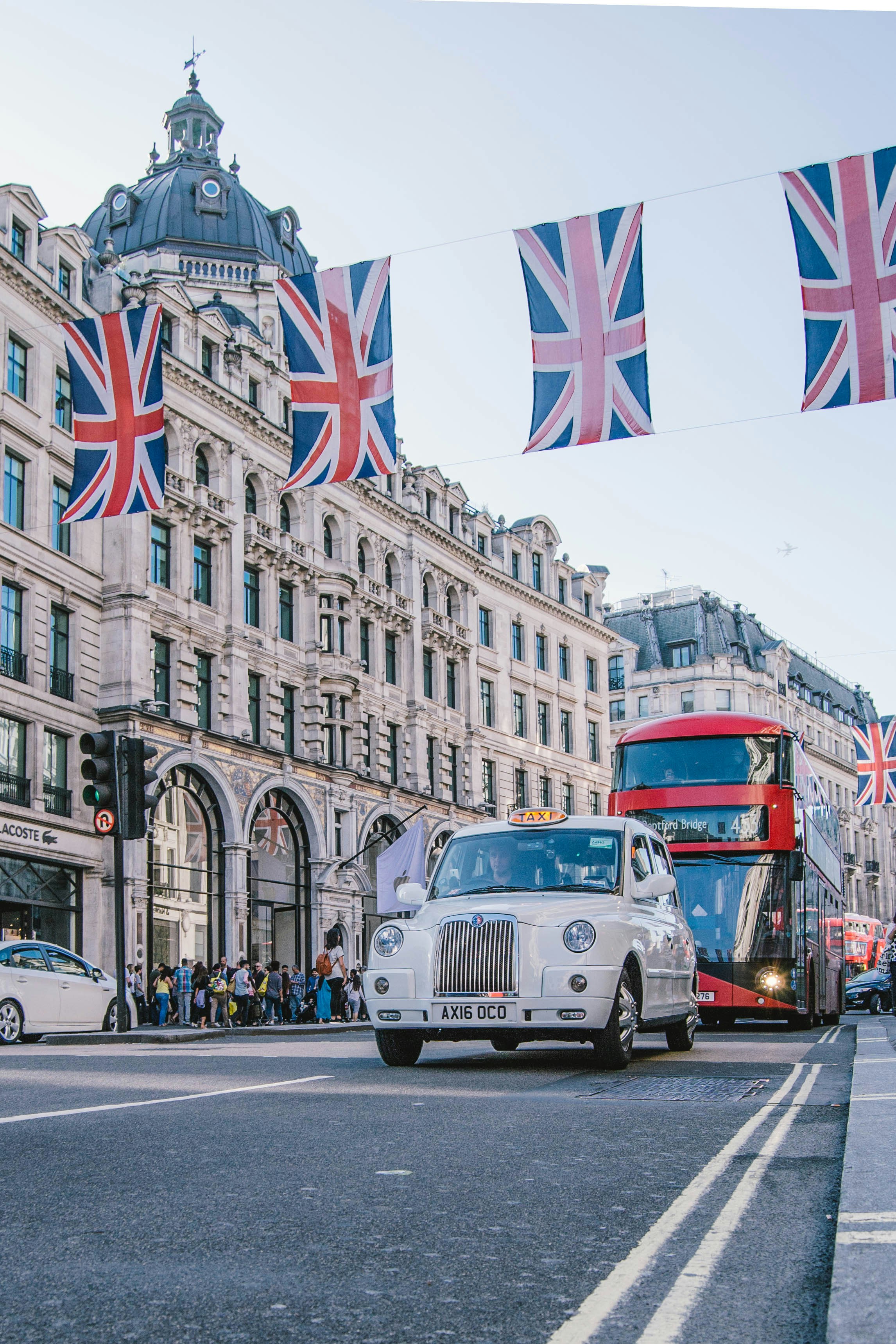 Regent Street decorated with Union Jack flags with passing London taxi and double-decker bus