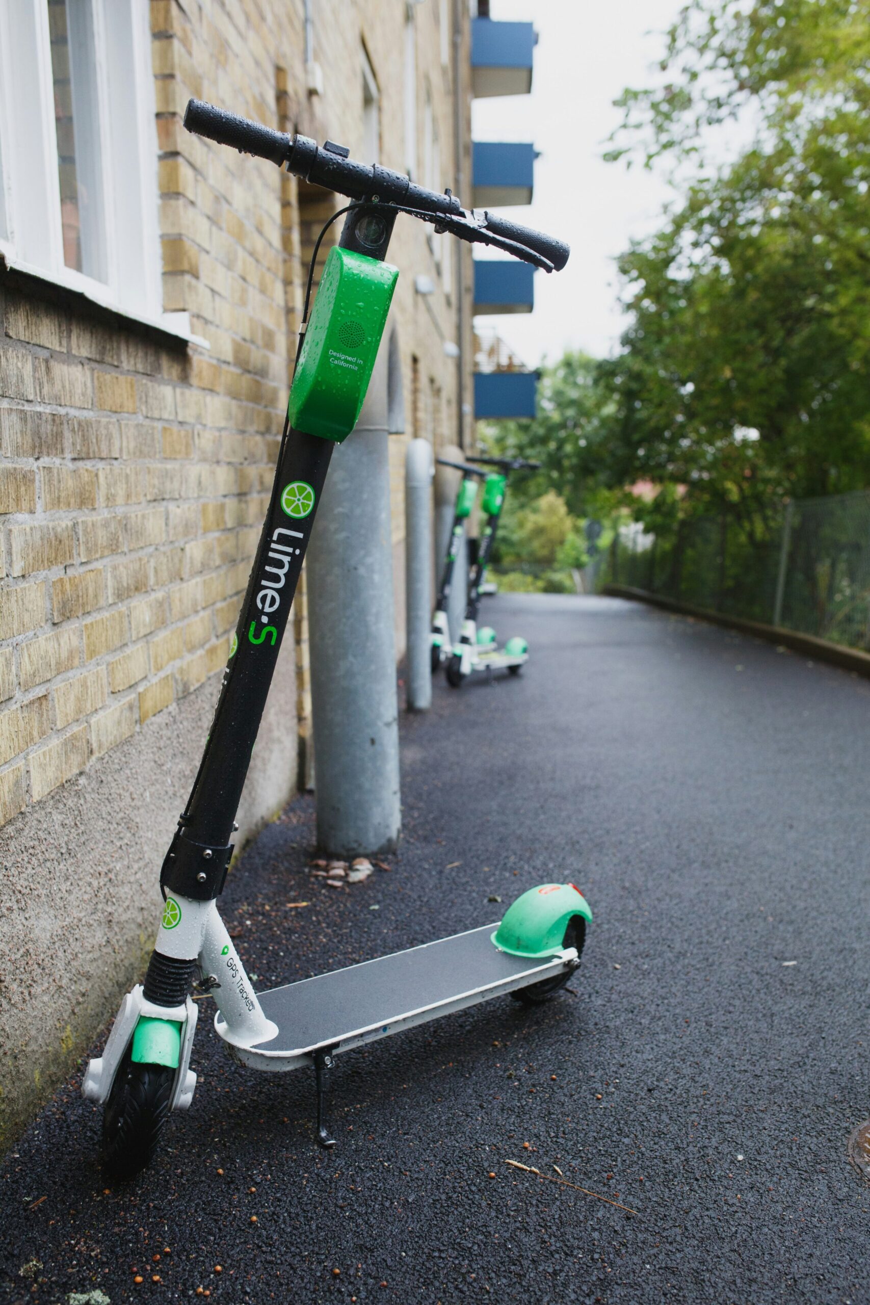 Lime-S electric scooter parked on an asphalt footpath beside a brick building
