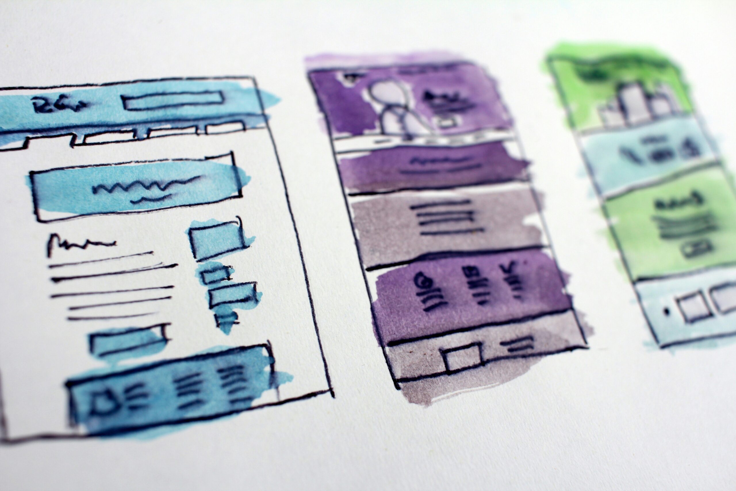 Hand-drawn watercolor sketches of website wireframes and UX layout structure on paper