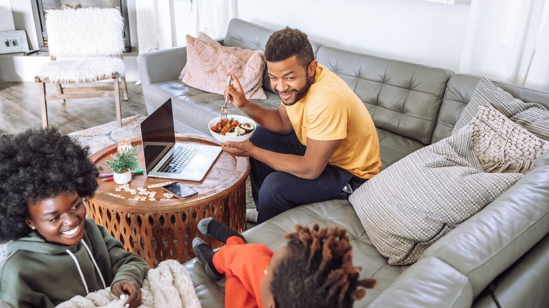 A family relaxing in a modern living room with a laptop, representing high-speed home broadband connectivity.