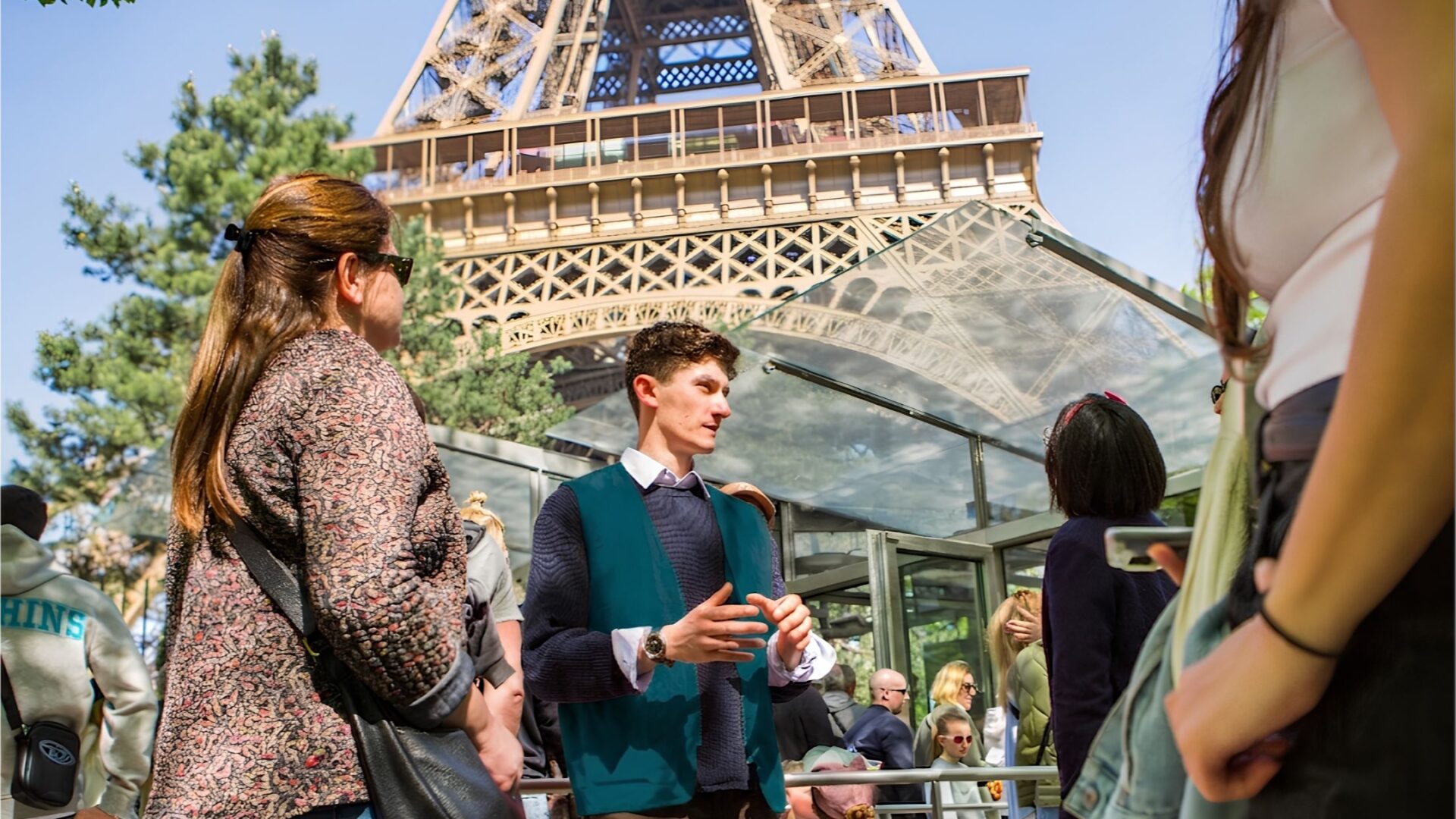 A tour guide speaking to a group of travellers in front of the Eiffel Tower in Paris, France.